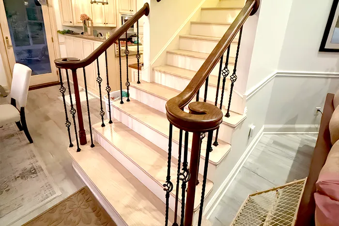 Remodeled staircase with a stained wood handrail and decorative wrought iron balusters
